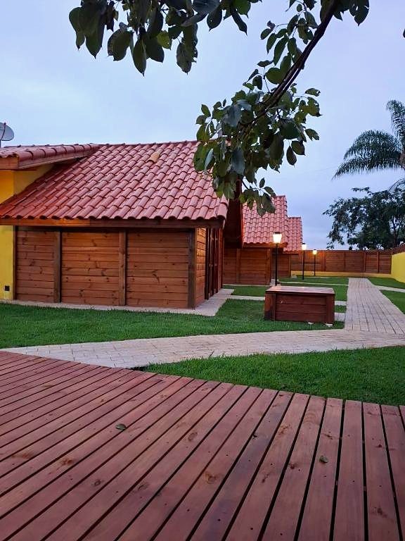 Chalés de madeira ao entardecer, com lampiões acesos e deck no jardim